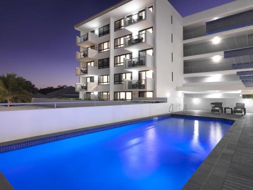 a building with a swimming pool in front of a building at Oaks Mackay Carlyle Suites in Mackay