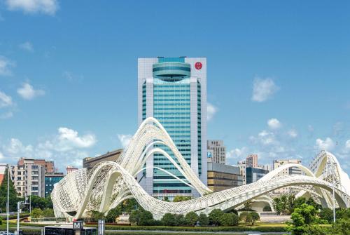 uma ponte branca em frente a um edifício alto em Ramada Plaza Optics Valley Hotel Wuhan (Best of Ramada Worldwide) em Wuhan
