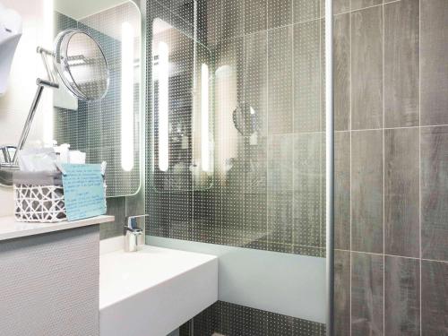 bagno con lavandino e doccia con specchio di ibis Bordeaux Mérignac a Mérignac