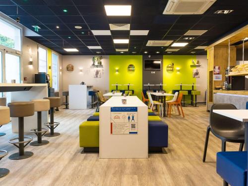 a restaurant with yellow walls and tables and chairs at ibis budget Paris Porte de Vanves in Vanves