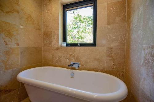 uma banheira na casa de banho com uma janela em Tresillian Lodge Waterfront, Forest, Hot tub,Sauna em Truro