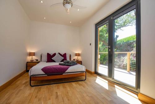 a bedroom with a bed and a large window at Tresillian Lodge Waterfront, Forest, Hot tub,Sauna in Truro