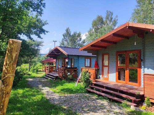 una pequeña casa con un porche junto a un patio en Bojkolandia en Ustrzyki Dolne