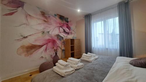 a bedroom with towels on a bed with a flower wall at Apartamenty Nadbrzeżna Premium 2 in Augustów