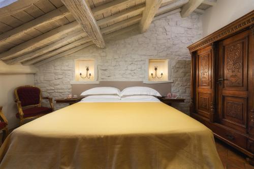 1 dormitorio con 1 cama grande de color amarillo y pared de piedra en Terrazza Silena, centro storico con vista Cortona!, en Cortona