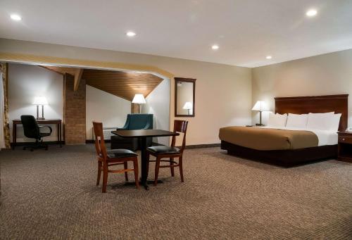 a hotel room with a bed and a table and chairs at Quality Inn in Grand Blanc