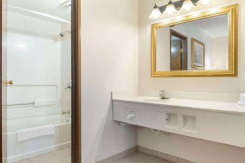 ein weißes Badezimmer mit einem Waschbecken und einem Spiegel in der Unterkunft Quality Inn & Suites in Manistique