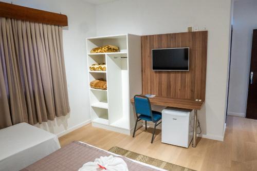 a room with a desk and a tv on a wall at Hotel Raul's in Gaspar