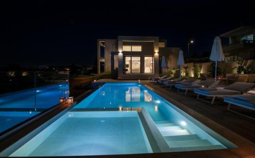 a swimming pool in front of a house at night at Villa Manu Luxury Living in Stalos