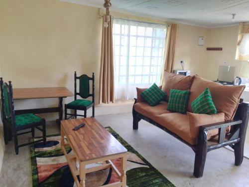 ein Wohnzimmer mit einem Sofa und einem Tisch in der Unterkunft Wooden Knee Cottages Nanyuki in Nanyuki