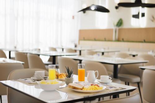 a dining room with tables with food and drinks at JR Hotels Gate 7 Bologna in Calderara di Reno