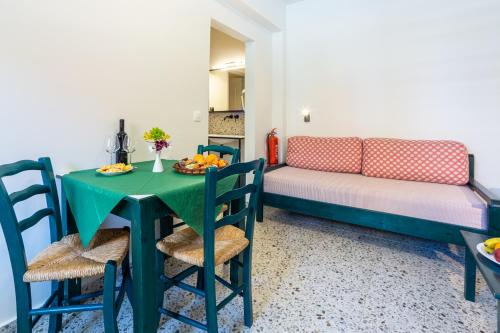 a dining room with a green table and a couch at Marelina Villas in Panormos Rethymno