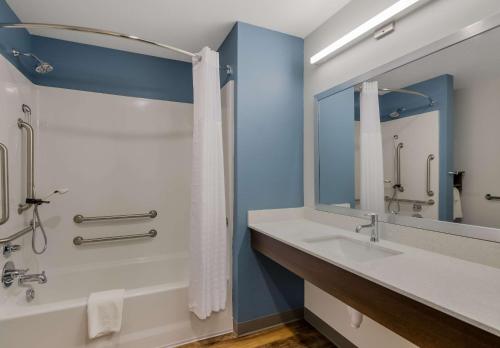 a bathroom with a sink and a shower and a mirror at WoodSpring Suites Roanoke in Roanoke