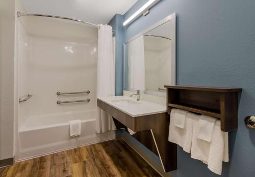 a bathroom with a sink and a tub and a mirror at WoodSpring Suites Roanoke in Roanoke