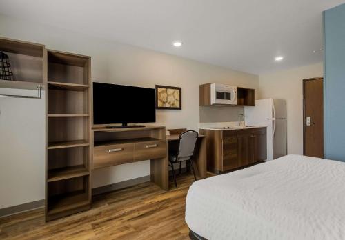 a hotel room with a bed and a desk with a television at WoodSpring Suites Roanoke in Roanoke