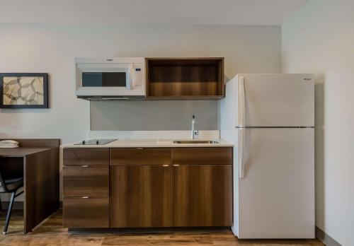 a kitchen with a white refrigerator and a microwave at WoodSpring Suites Roanoke in Roanoke
