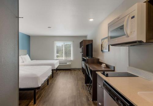 een kleine hotelkamer met 2 bedden en een keuken bij WoodSpring Suites Roanoke in Roanoke