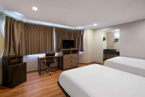 a hotel room with a bed and a desk and a television at Econo Lodge in Vallejo