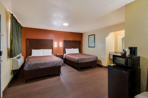a hotel room with two beds and a tv at Rodeway Inn & Suites East in New Orleans