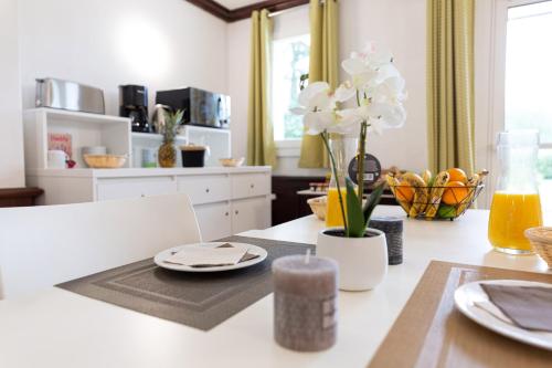 een keuken met een tafel met borden en bloemen erop bij Résidence Goélia Green Panorama in Cabourg