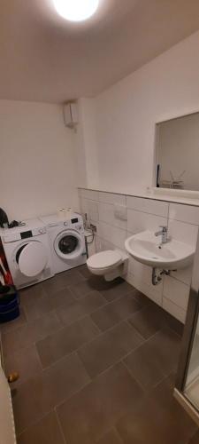 a bathroom with a sink and a washing machine at Penzini Apartment in unmittelbarer Nähe zur Messe Karlsruhe in Rheinstetten