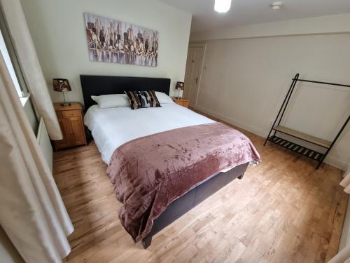 a bedroom with a large white bed and wooden floors at Gap Retreat in Carrickmore