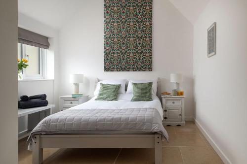 a bedroom with a bed with green pillows at Farmyard Cottage in Malmesbury