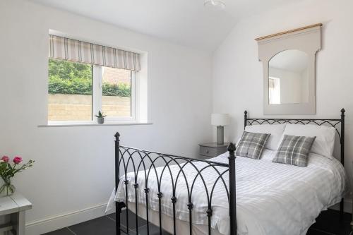 een slaapkamer met een zwart bed en een spiegel bij Little Calf Cottage in Malmesbury