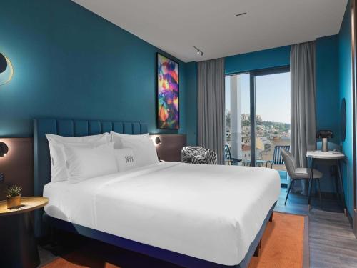 a bedroom with a white bed and a blue wall at NYX Esperia Palace Hotel Athens by Leonardo Hotels in Athens