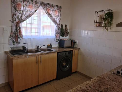 a kitchen with a washing machine and a sink at Weavers Nest 34 in Windhoek