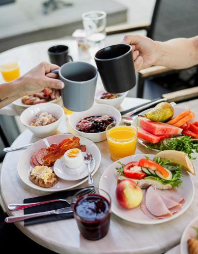 a table with plates of food and cups of coffee at Hotel Emilia in Hämeenlinna