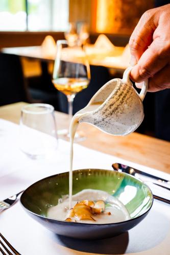 a person is pouring gravy into a bowl of food at Alpin Peaks in Turracher Hohe