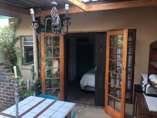 une terrasse avec une porte s'ouvrant sur une chambre avec un lit. dans l'établissement Garden Room At Schilbach House, à Parys