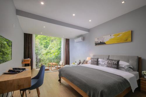 una camera con letto, scrivania e finestra di Garden Villa Resort Yangshuo a Yangshuo