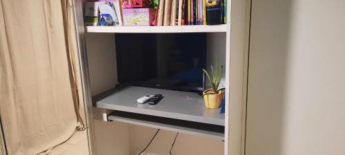 uma televisão numa estante de livros com um controlo remoto em Chambre d'hôte chez Aurélie et Jean-Christophe em Simpson Bay