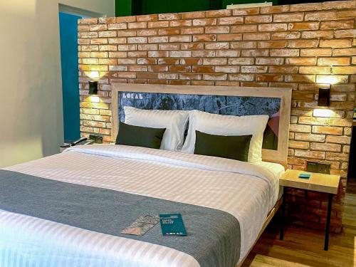 a bedroom with a large bed with a brick wall at LOKAL Rooms x Murree Kashmir Point in Murree