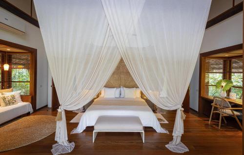 a bedroom with a bed with white curtains at Nay Palad Hideaway - All Inclusive Stay in General Luna