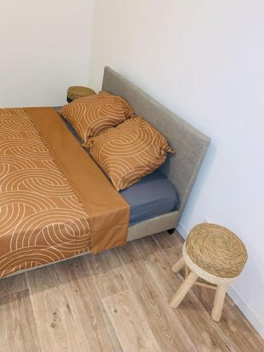 een bed met 2 kussens en een kruk in een kamer bij Superbe appartement en rez-de-chaussée in Roanne