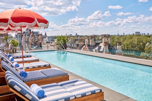 a pool on the roof of a building with lounge chairs and an umbrella at The Berkeley in London