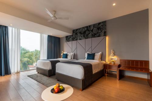 um quarto de hotel com duas camas e uma mesa com fruta em De Mandarin Candolim Beach Goa em Candolim