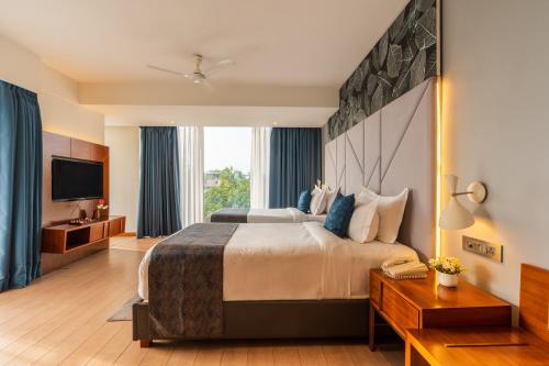 a hotel room with a large bed and a television at De Mandarin Candolim Beach Goa in Candolim