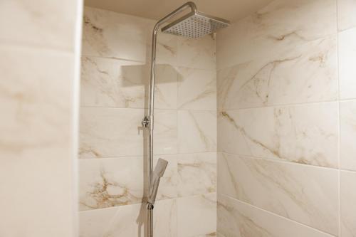 a bathroom with a shower with white marble walls at La villa events in Amaliás