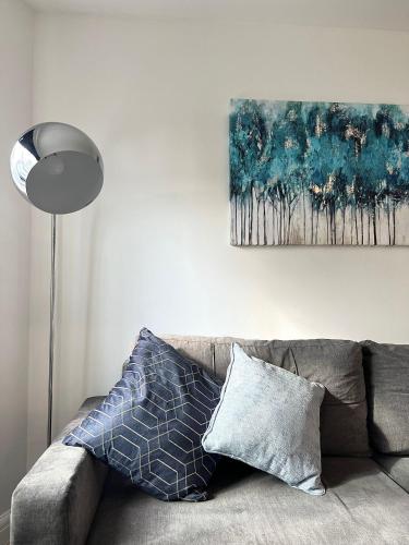 a couch with two pillows and a painting on the wall at Central Watford Duplex in Watford