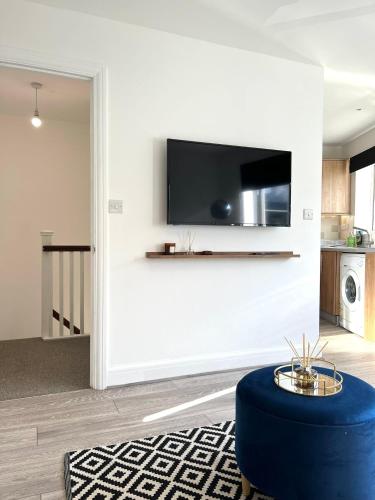 a living room with a tv and a blue ottoman at Central Watford Duplex in Watford