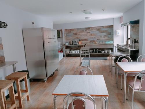 a kitchen with tables and chairs and a refrigerator at Belfast International Youth Hostel in Belfast