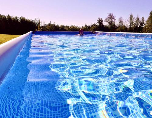 a large blue swimming pool with a person in it at Bathsheba, Luxurious Shepherds Hut set in Todber a hamlet set in Thomas Hardy's iconic rural Dorset in Todber