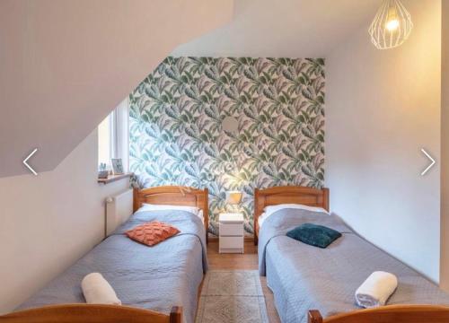 two twin beds in a room with a wall at Apartamenty Przy Deptaku in Karpacz