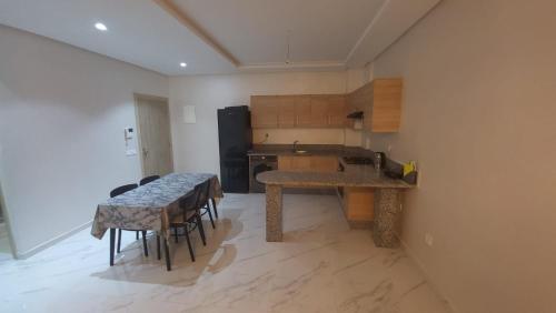 a kitchen with a table and some chairs in it at Zenata Tower Ain Harrouda Mohemadia in Mohammedia