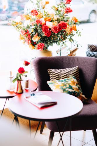 um quarto com duas mesas e uma cadeira e um arranjo de flores em Molo Rouge em Wunsiedel