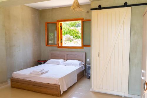 1 dormitorio con 1 cama y puerta corredera en Exoristoi Nature Suites, en Gavdos